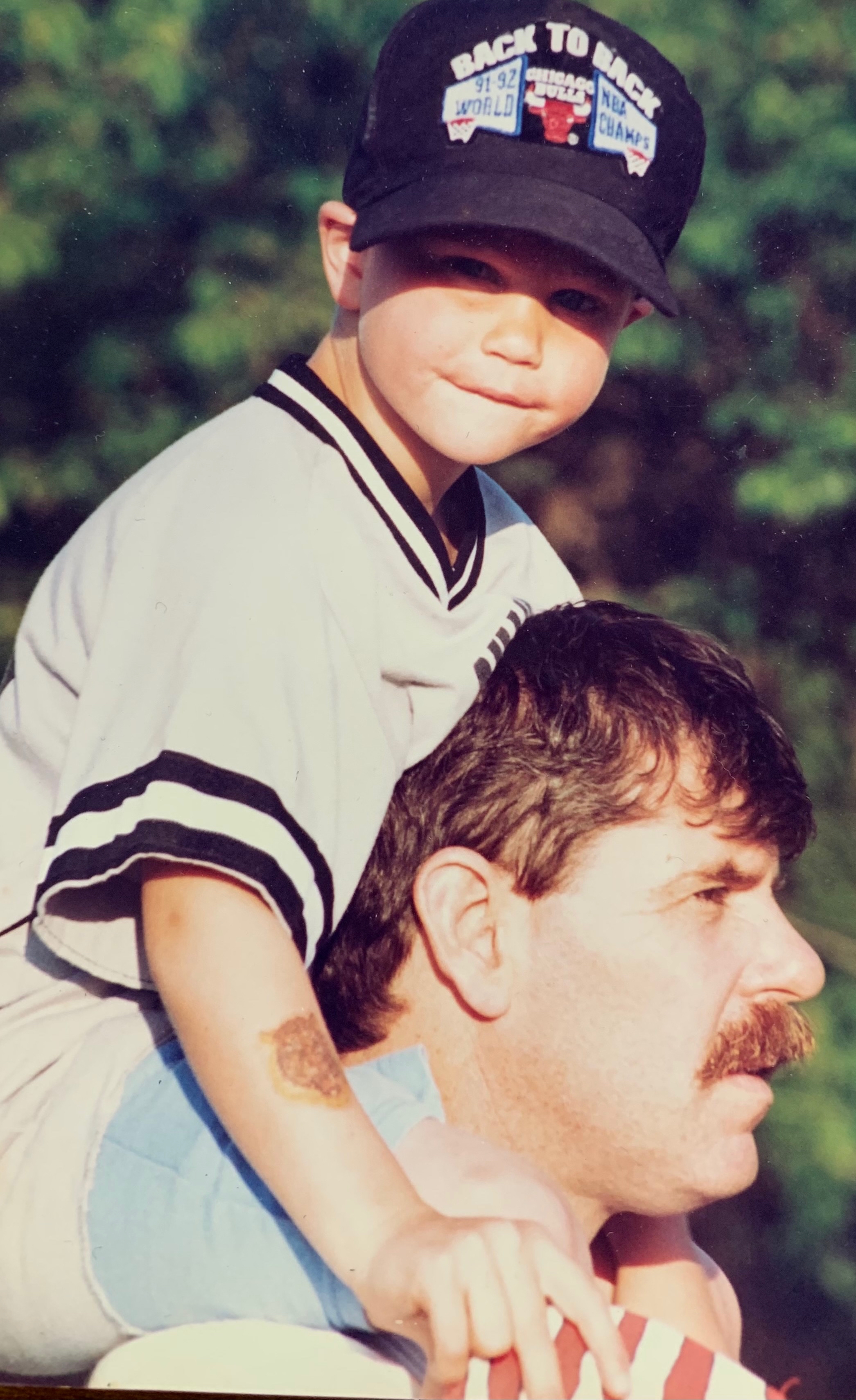 Rick Bickford coaching a baseball game with Nathan on his shoulders