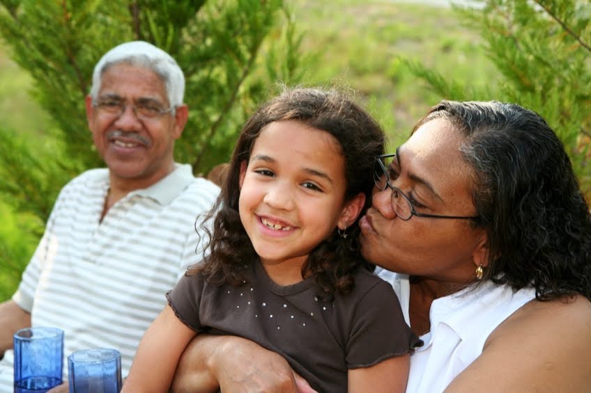 Photo of grandfather and grandmother, with grandchild in the grandmother's lap.
