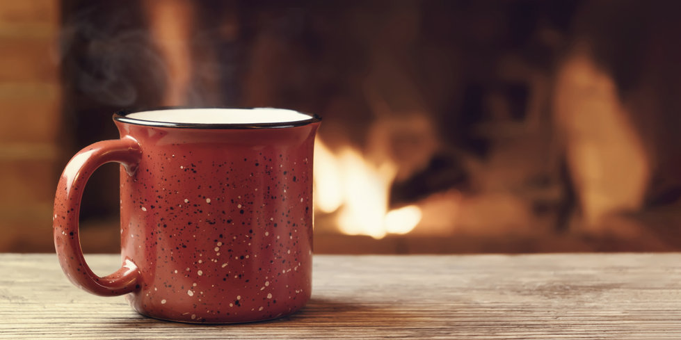 Hot cup of liquid on a counter with fireplace in the background