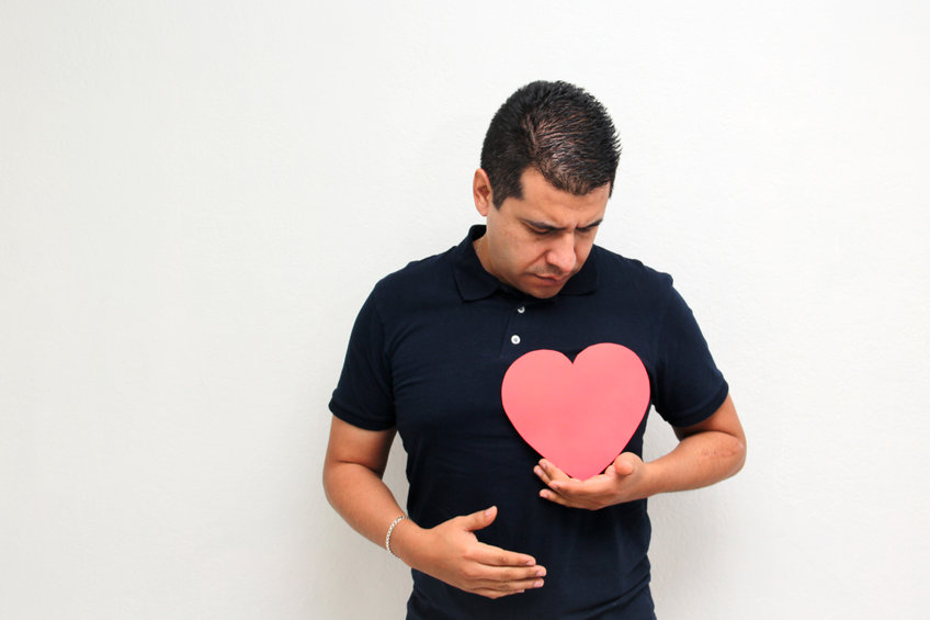 Man in a dark blue shirt with a red paper cut out heart propped on his chest